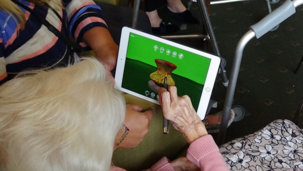 Photo of a woman using an Ipad to draw patterns on a vase
